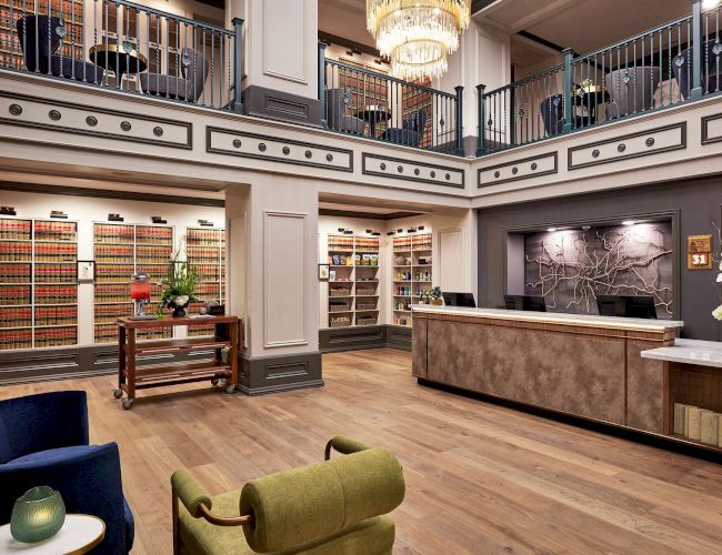 A luxurious reception area with chandeliers, ornate railings, and shelves packed with colorful products in a stylish interior.